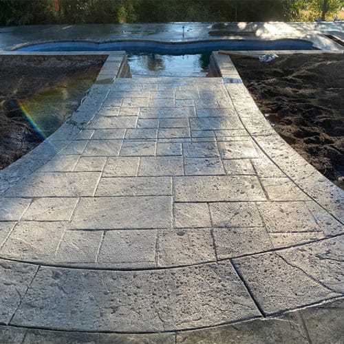 Stamped concrete walkway leading to a pool