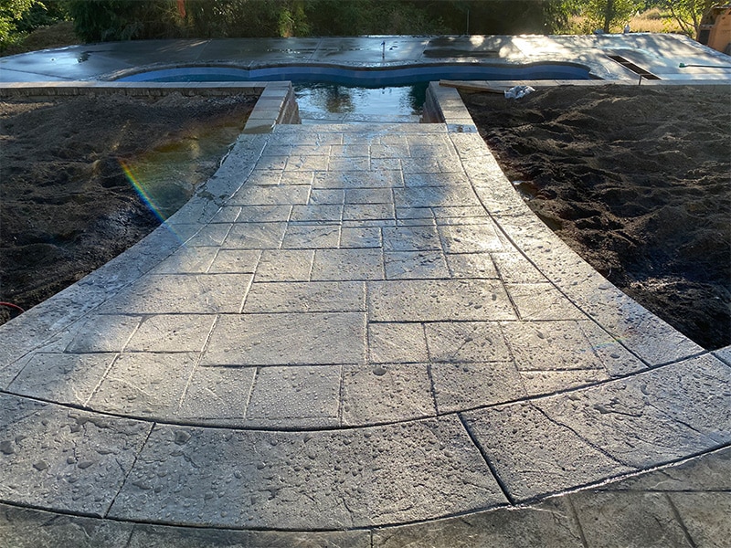 Stamped concrete walkway leading to a pool