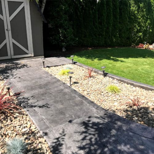 Stamped concrete walkway leads to a shed