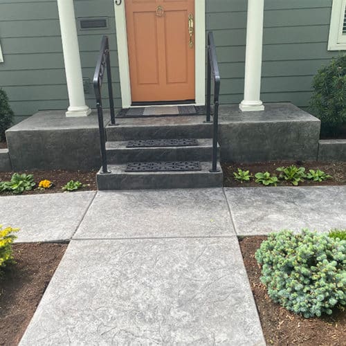 Stamped concrete walkway leads to steps and home entrance