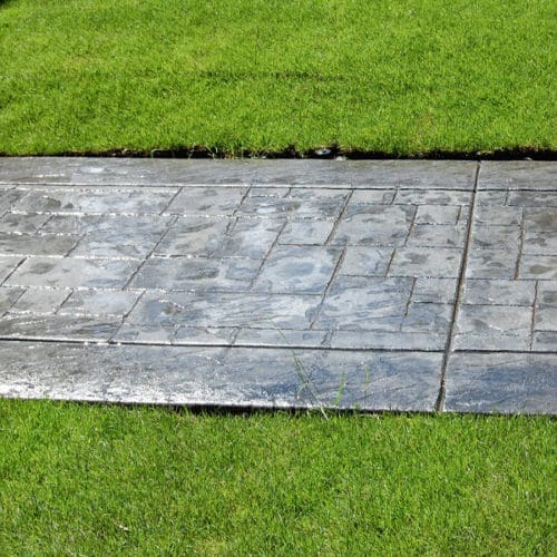 Stamped concrete walkway surrounded by grass