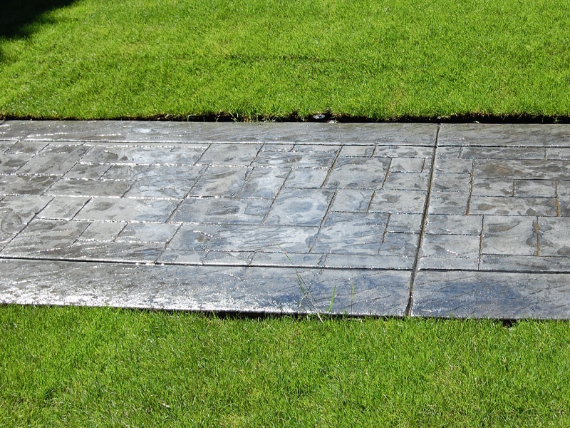 Stamped concrete walkway surrounded by grass