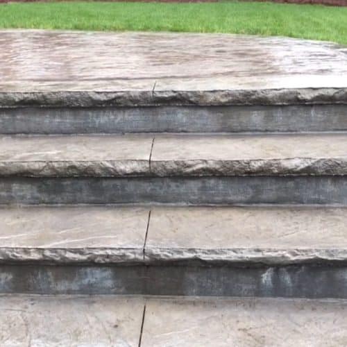 Steps to a home lead to a stamped concrete walkway