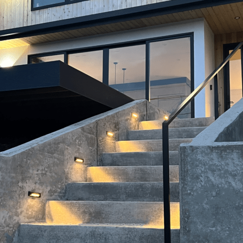 Retaining walls with lighted steps leading to a custom home. Concrete steps and walkways by Allison Concrete