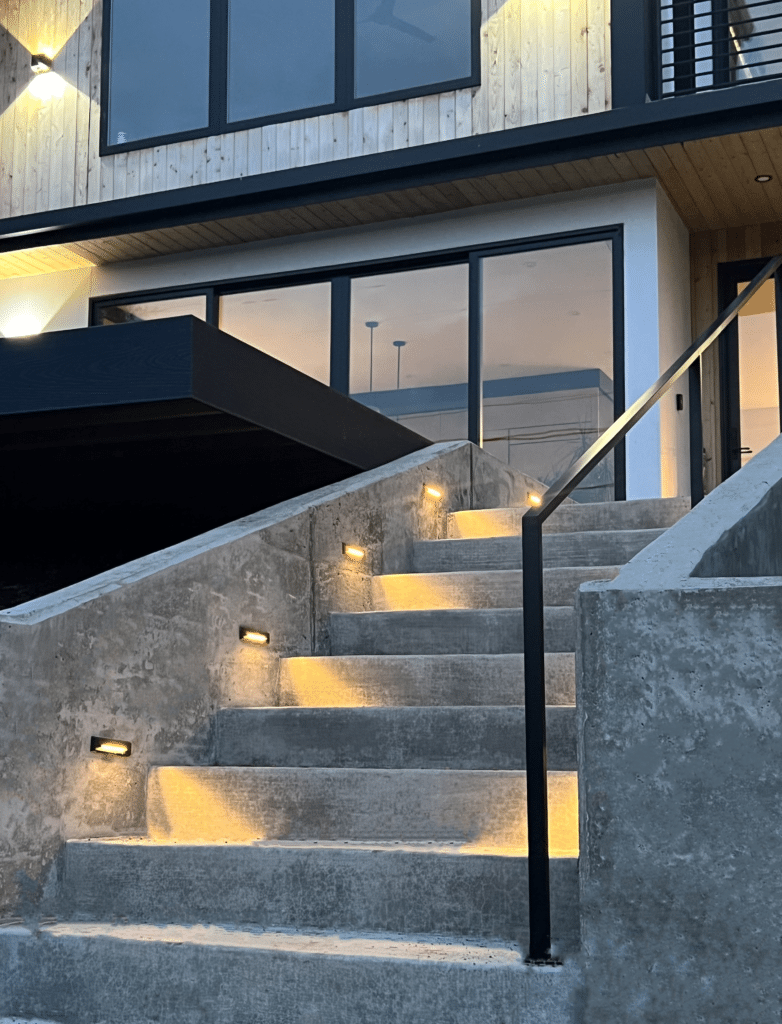 Retaining walls with lighted steps leading to a custom home. Concrete steps and walkways by Allison Concrete