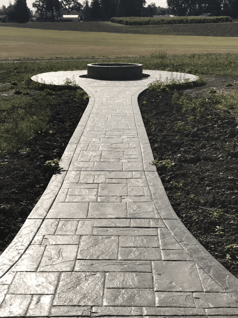 Stamped concrete walkway leads to a planter